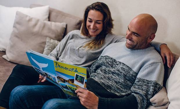 A couple sitting on a couch reading a brochure on Denmark