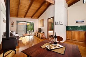 Wooden floor and ceiling and a native Jarrah table in the lounge / dining of Rumi accommodation.