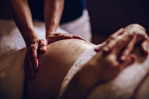 Hands massaging a pregnant belly.