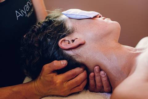 A masseuse holding a woman's neck.