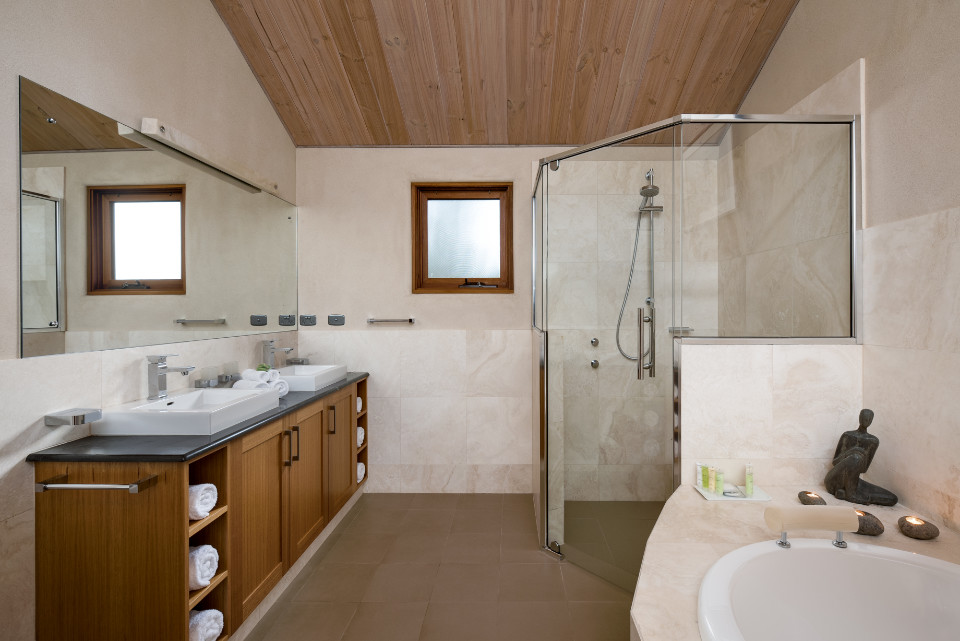A wonderfully bright white tiled bathroom with spa, shower and wooden vanity.