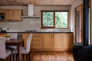 A wooden featured kitchen with a window to the native bush