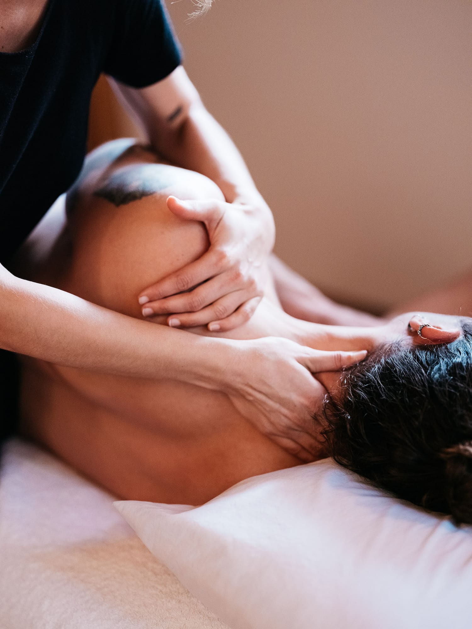 Hands on the neck and shoulder of a person getting a massage.